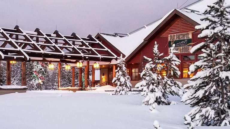 The Old Faithful Lodge sits covered in snow, a popular lodging destination during winter adventures.