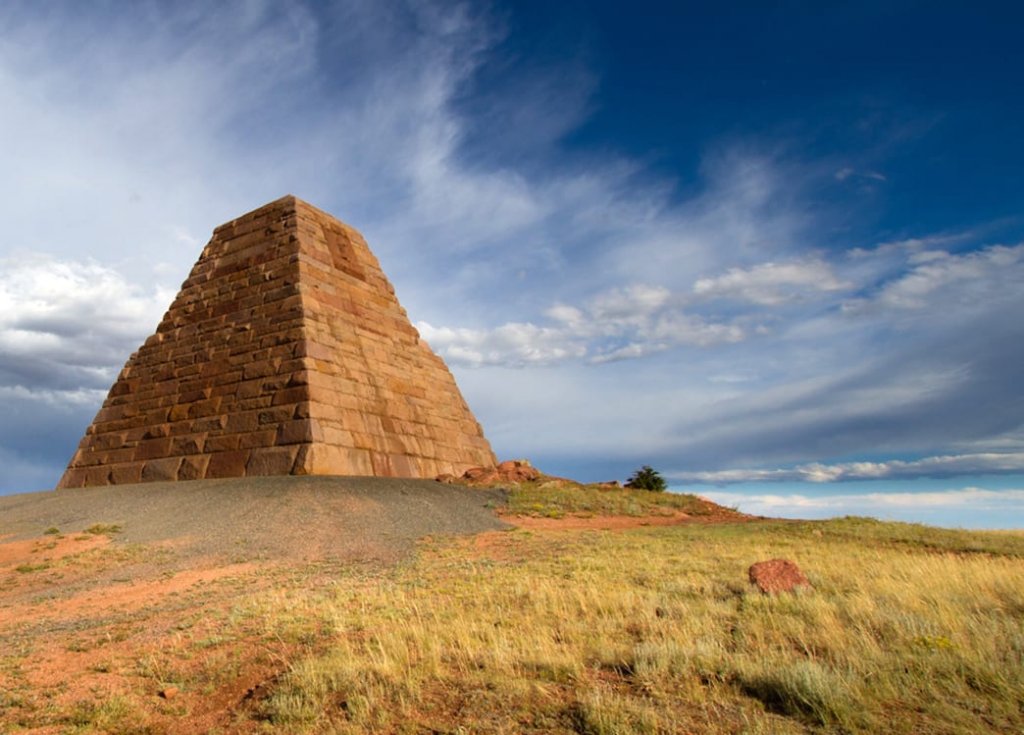 A stone pyramid stands on a mound in grassy plains, a weird and unique place to visit in Wyoming.