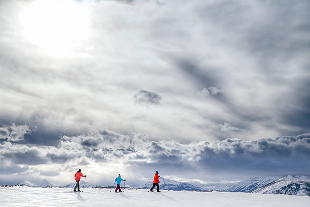 Visitors cross-country ski as mountains peek through in the distance in Yellowstone National Park.