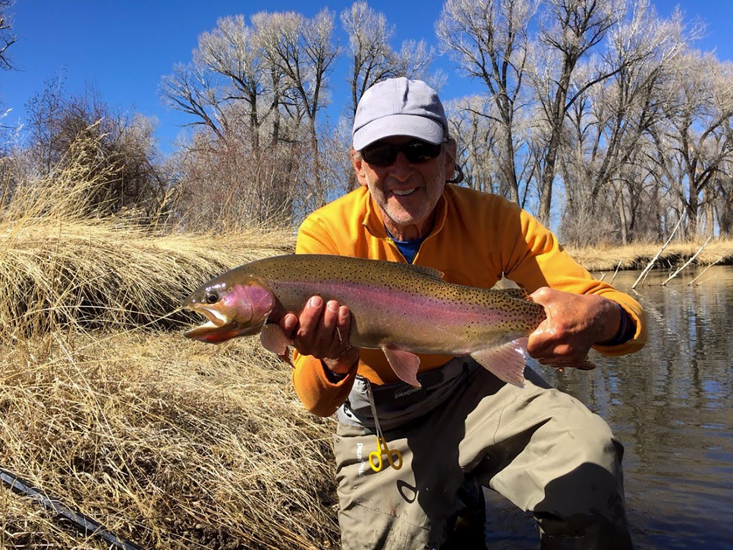 Man holding a fish out of water by the North Platte River in Wyoming.