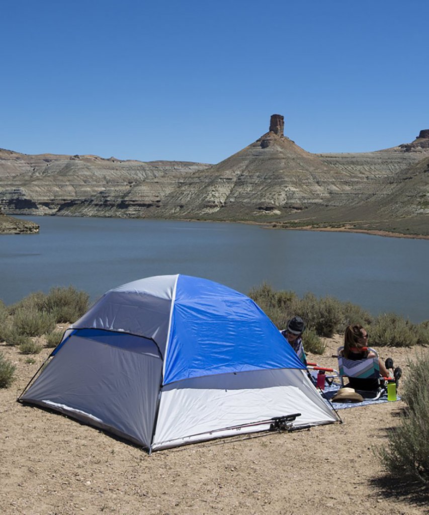 A couple with a campsite set up in front of a beach at Flaming Gorge Reservoir at Buckboard Marina in Wyoming