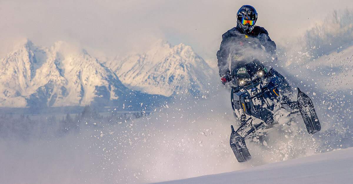 Snowmobiler jumping in the snow.