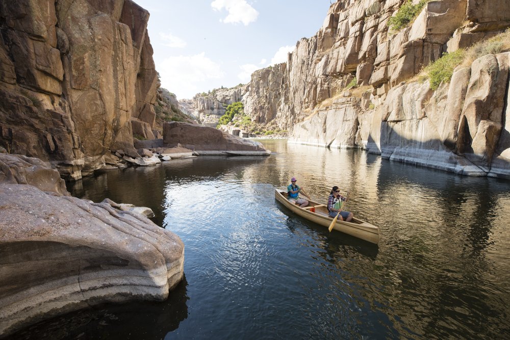 Boaters floating on river water in canyon