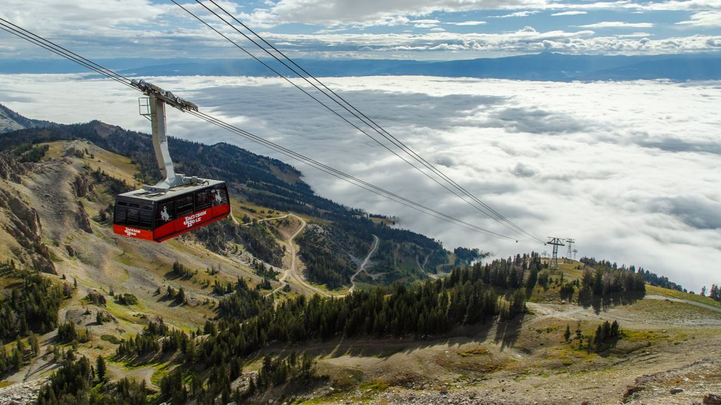 The red aerial tram soars through captivating views of the landscape sprawling across Jackson Hole Mountain Resort. 