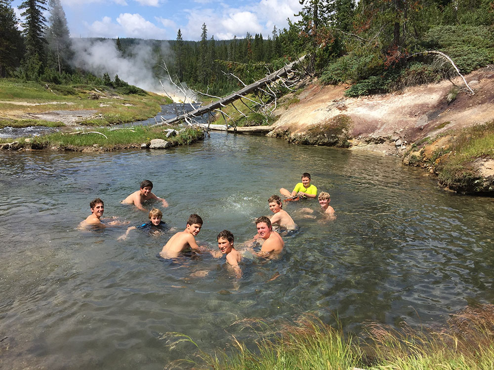 A group of youths laugh and as they go swimming in Yellowstone National Park's Mister Bubbles.