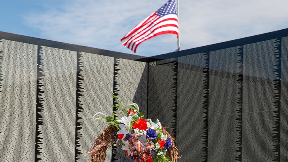 American flag flying over memorial wall