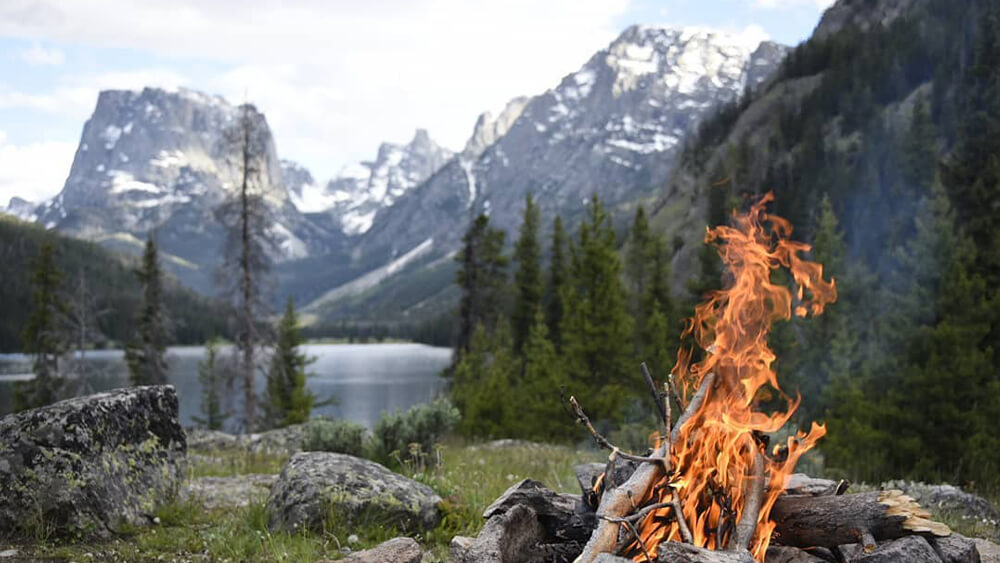 Campfire burning with mountain backdrop