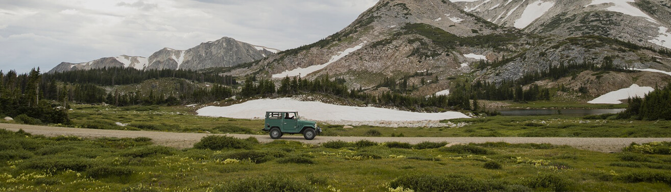 Green Jeep driving through the Medicine Bow mountains.