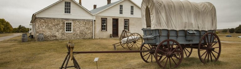 Covered wagon parked in front of a building at Fort Laramie.