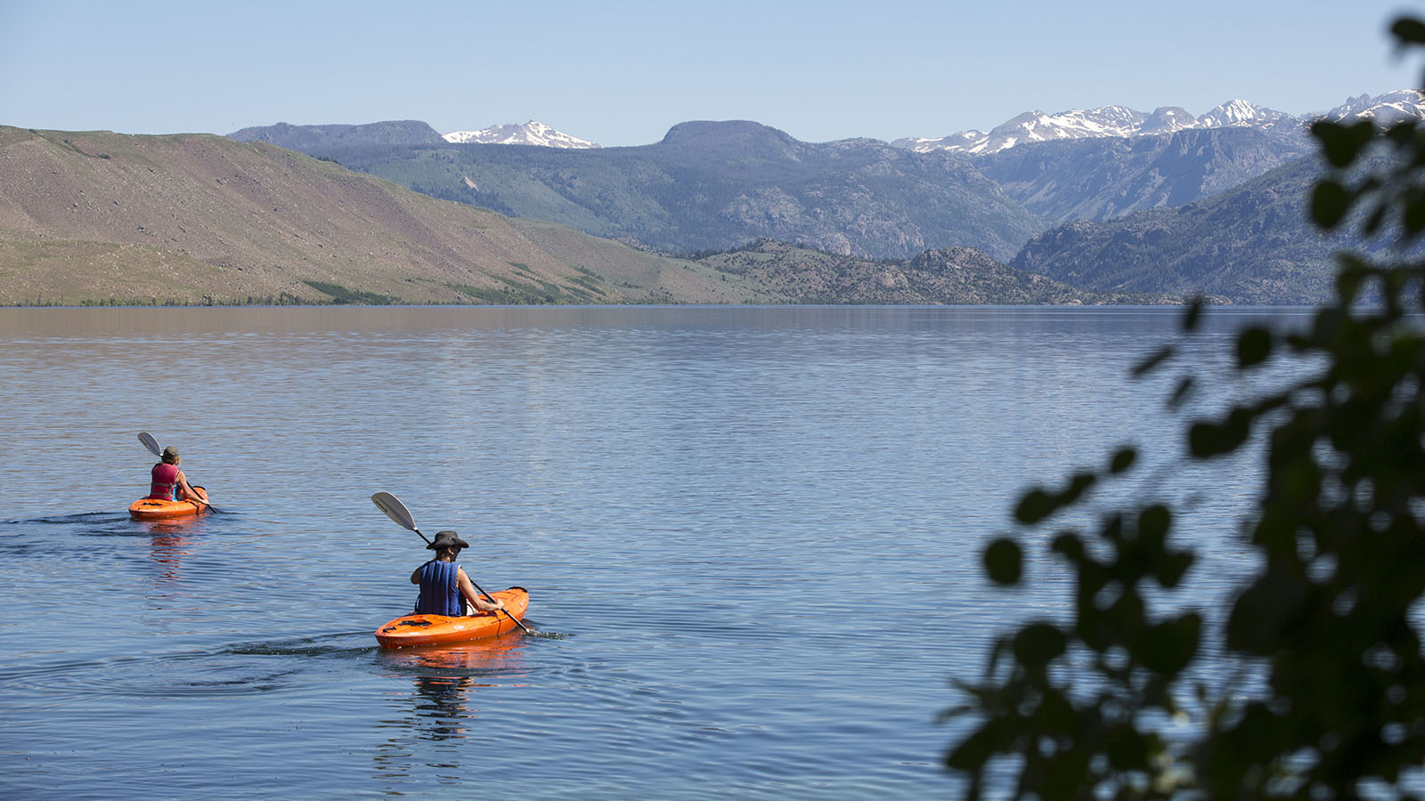 Two kayakers on the lake with mountains in the background