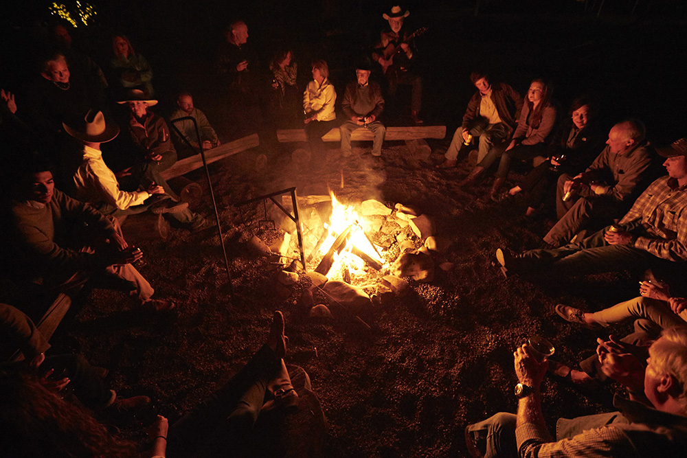 A group of people around a campfire at a dude ranch