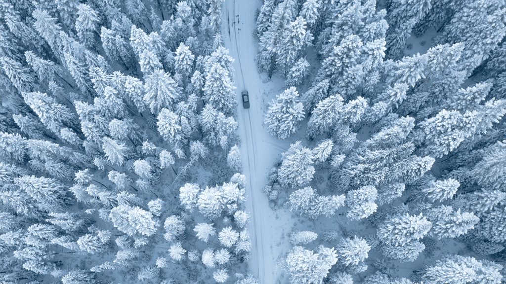 Aerial view of car driving downm a snowy road in Wyoming winter.