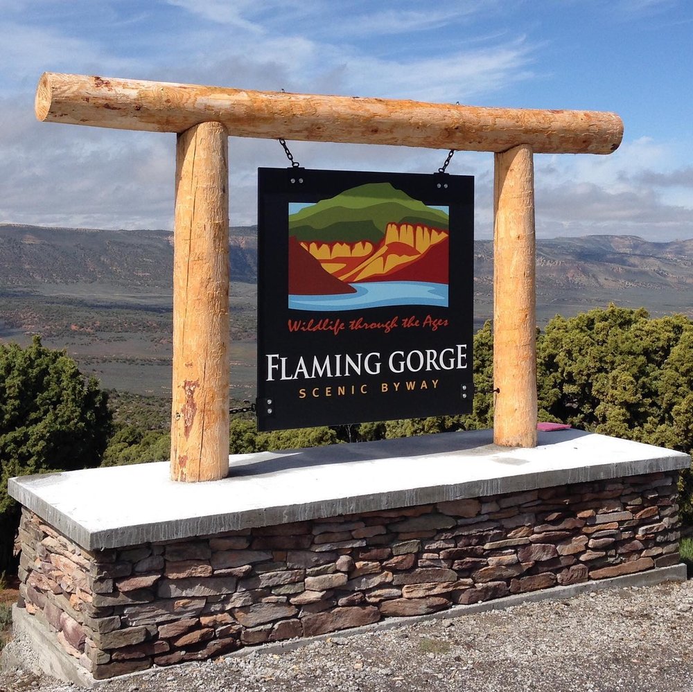 Sign of Flaming Gorge Green River Basic Scenic Byway with a mountain range behind it in Wyoming