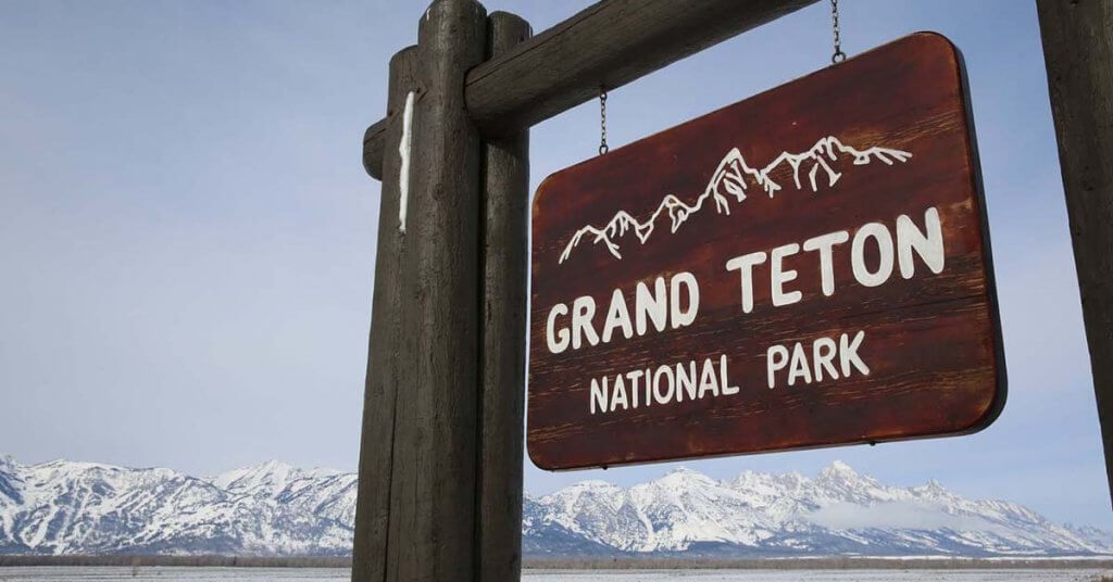 A wooden sign at the entrance of Grand Teton National Park invites in visitors and guests with its many fun things to do.