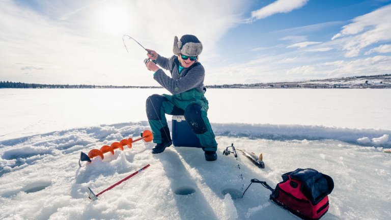 11 Winter Events that Highlight the Season in Wyoming - Ice fisherman catching a fish.