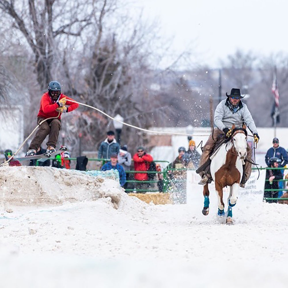Athlete skiijoring during the Sheridan WYO Winter Rodeo, a popular winter event.