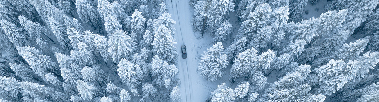 Aerial view of a car driving down a wintery road