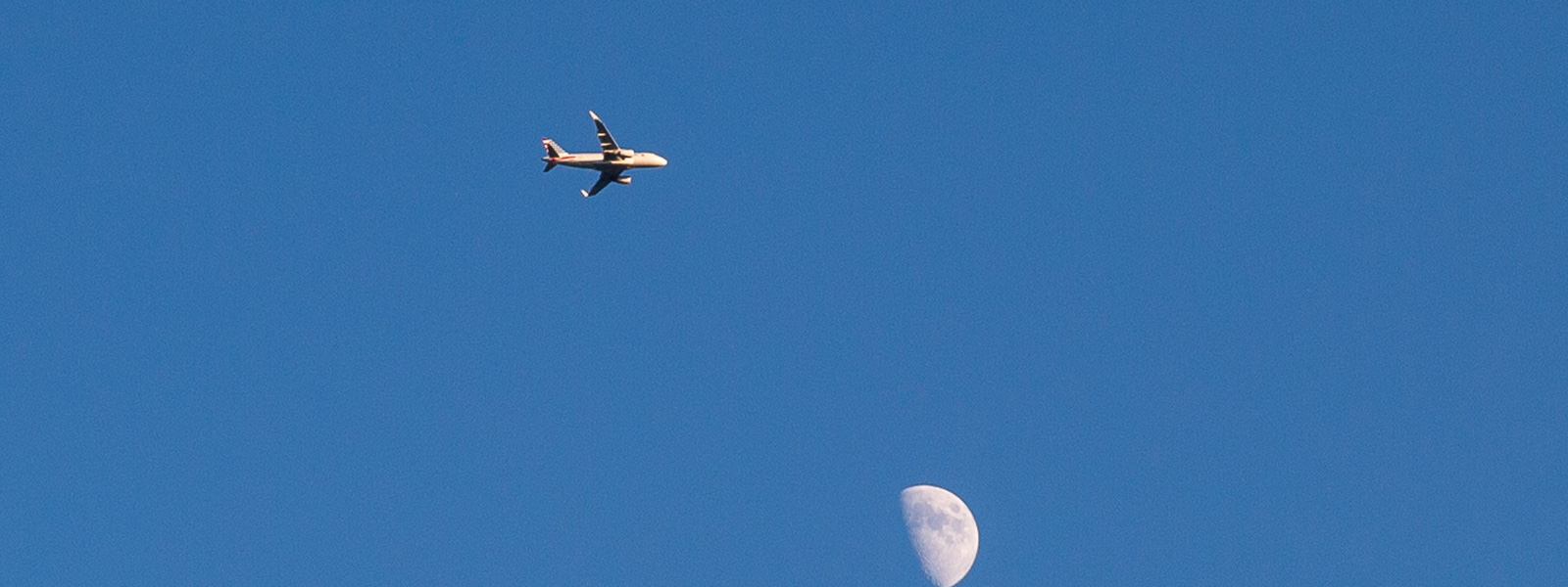 Airplane flying in sky next to moon