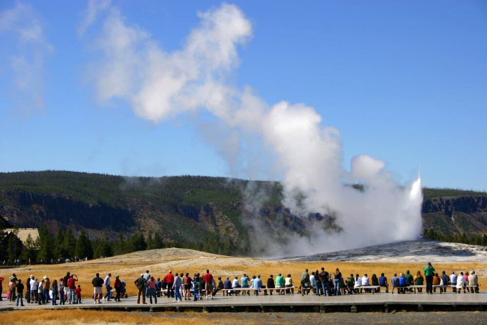 Old Faithful Geyser erupting in front of a crowd.