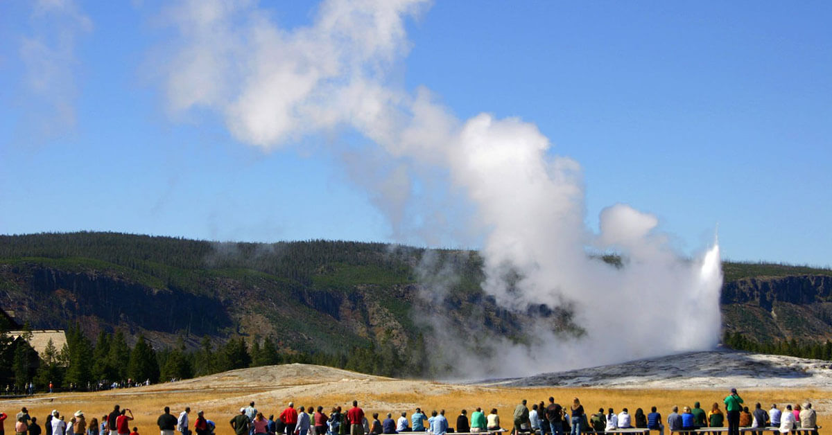 Crowds of people gather outside a geyser at Yellowstone.