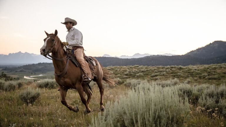 Cowboy riding a horse through the prairie - Experience Wyoming's Notorious Outlaw History