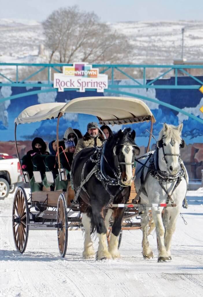 Horses pull a carriage in snowy downtown Rock Springs, a lovely Christmas activity for the family.