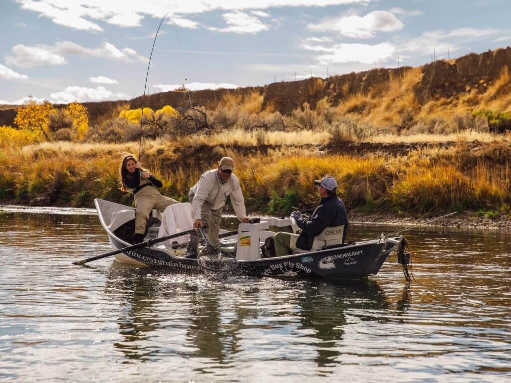 Three people fly fishing on a boat, a popular activity on the North Platte River.