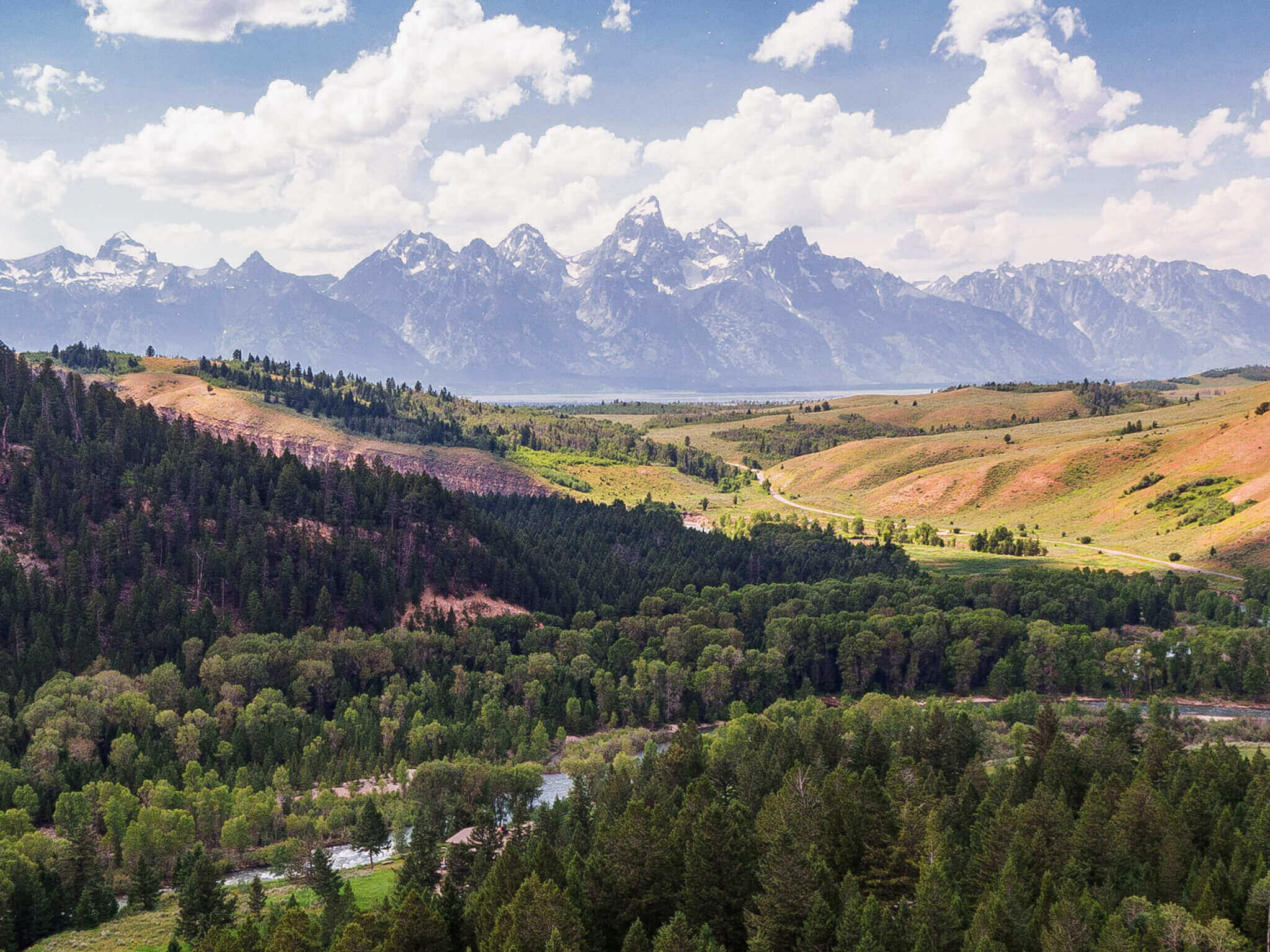 An overhead view of the sprawling forests and snow-capped mountains in the distance at Grand Teton National Park.