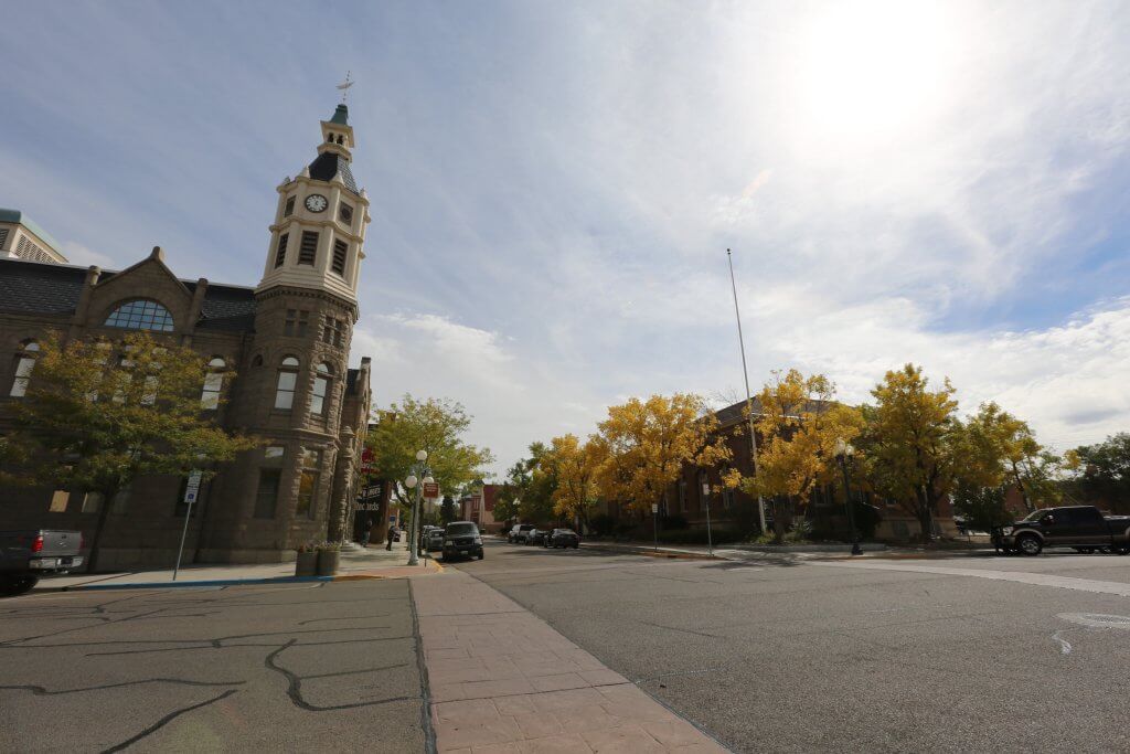 A view of the main street in Rock Springs, Wyoming where the Rock Springs Historical Museum clock tower stands tall from the original Rock Springs City Hall as colorful trees pop along the street. 