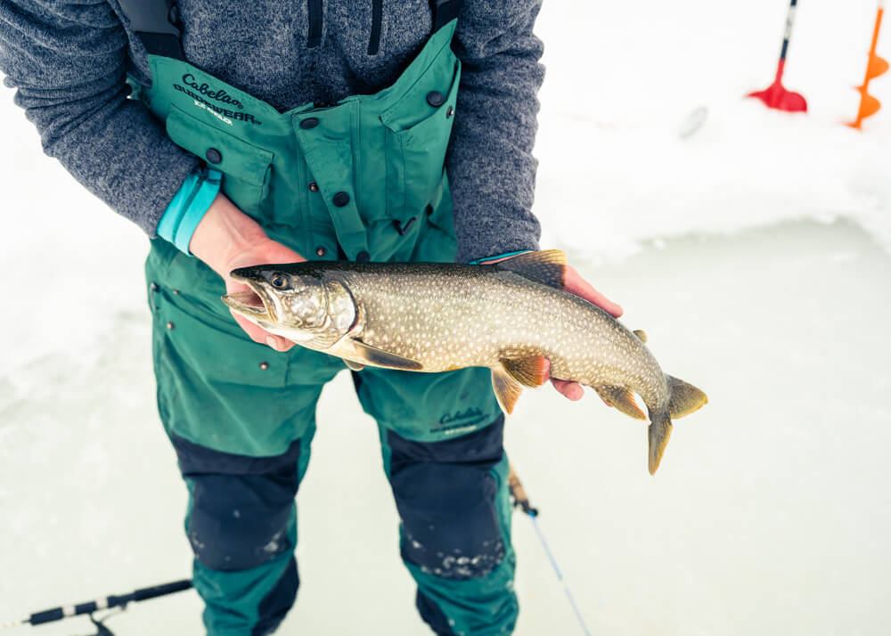 A man holding a fish caught while ice fishing in Wyoming.