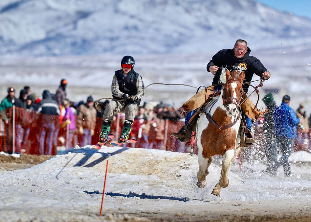 An athlete partakes in a skijoring competition in Wyoming, a top event to see during your winter vacation.