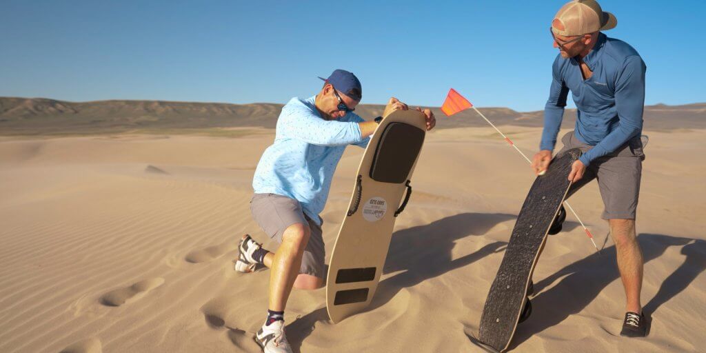 Two men check out their sandboarding equipment as they get ready to sand surf in Wyoming.