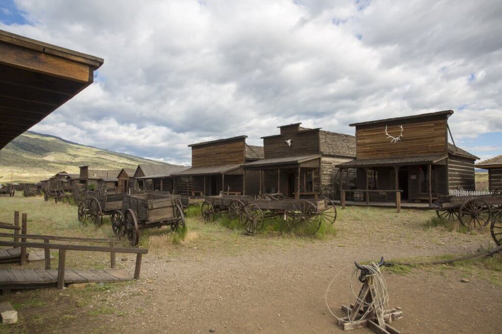A large group of wooden wagons in front of a row of historic wooden buildings at Old Trail Town.