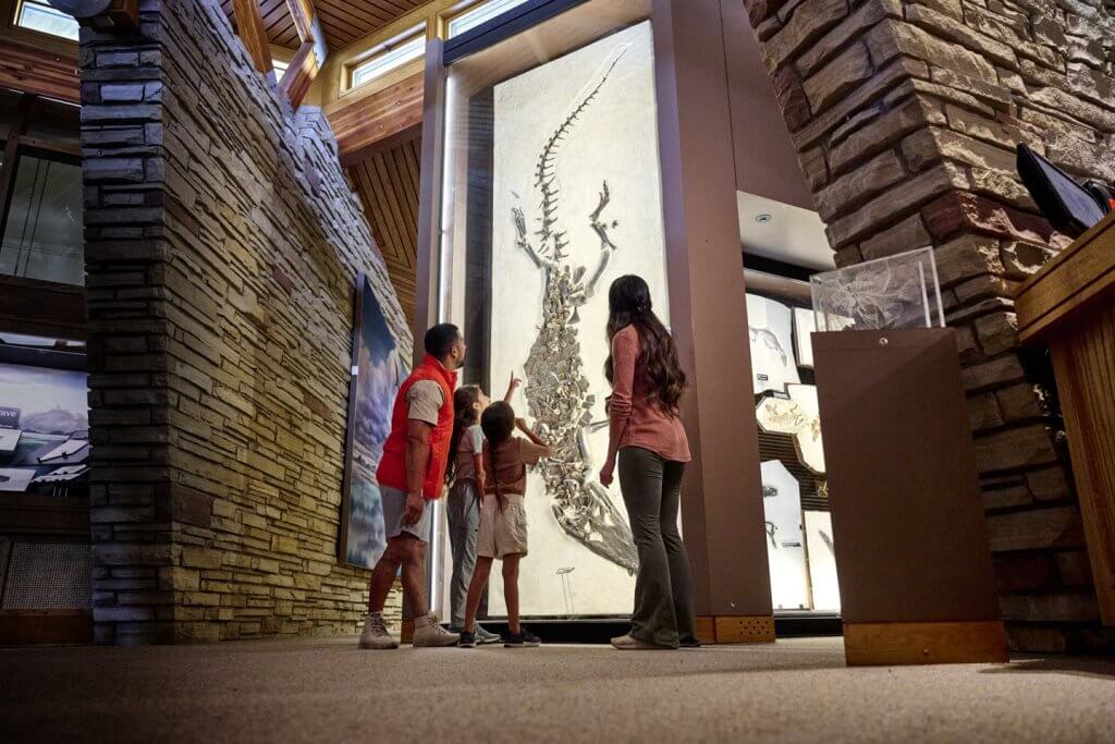 A family looks up at the Fossil Butte National Monument, as a young girl points in amazement at the fossil exhibit before them. 