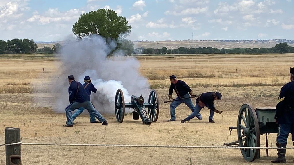 A cannon blows off smoke across the field as officials dressed in military outfits participate in a demonstration at the Fort Laramie Historical Site in Fort Laramie, Wyoming.
