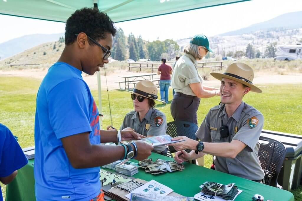 A National Park Ranger hands a boy a pamphlet at Yellowstone National Park.
